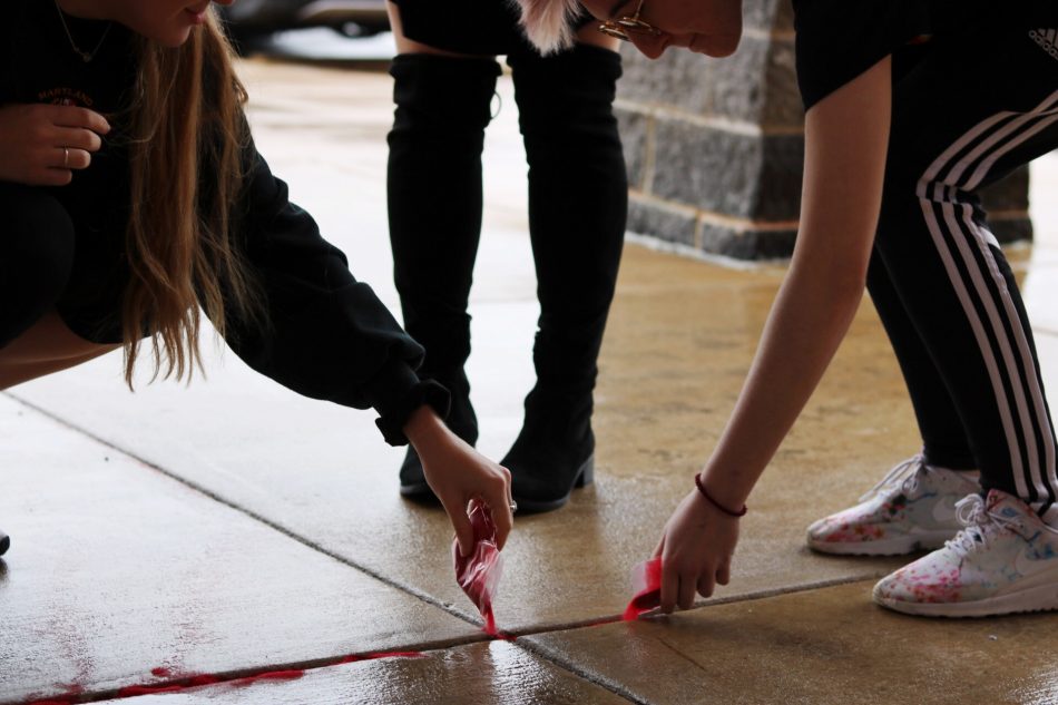 Students fill in the cracks with red sand.