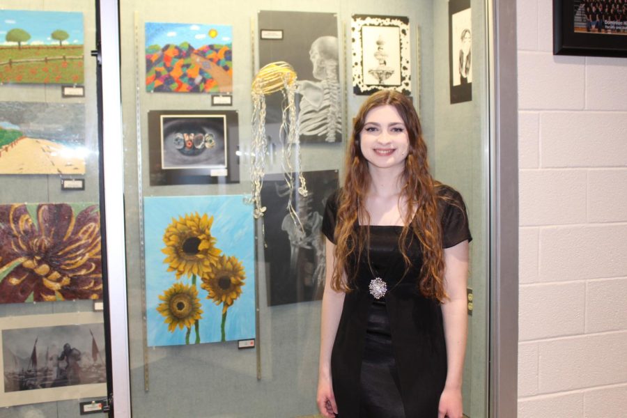 Ella Greer posed next to her artwork at Evening with the Arts where she performed with Titan Singers Choir.